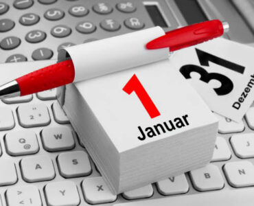 Kalender Symbolfoto zum Jahreswechsel: Kalenderblätter mit 31. Dezember und 1. Januar auf Tastatur, daneben Kugelschreiber und Taschenrechner